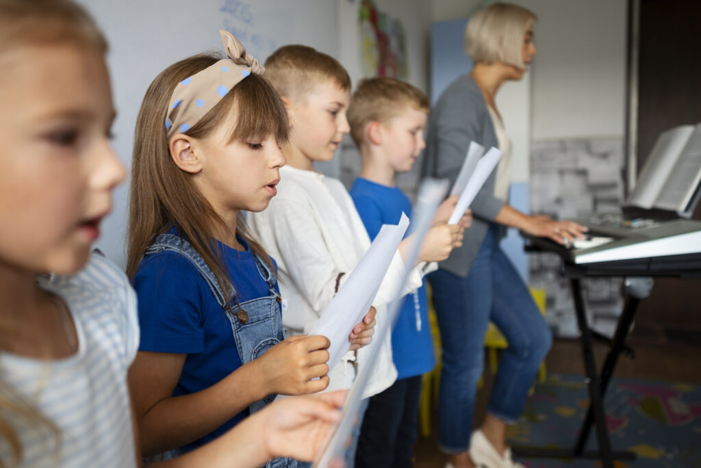 Lapsia laulamassa nuoteista, kun opettaja soittaa pianoa