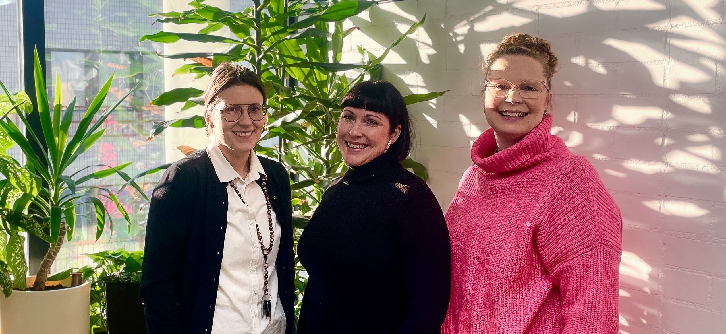 Kolme ihmistä hymyilee vierekkäin